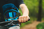 Hand, handle and cycling with helmet, sports and person in forest, mockup space and closeup. Mountain bike, biker outdoor and travel with adventure, fitness and ready to ride, exercise and training