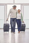 Mature couple, suitcase and walking in airport lobby, happy and travel together on tourist holiday. Man, woman smile and luggage for flight on vacation, immigration journey and global airplane trip