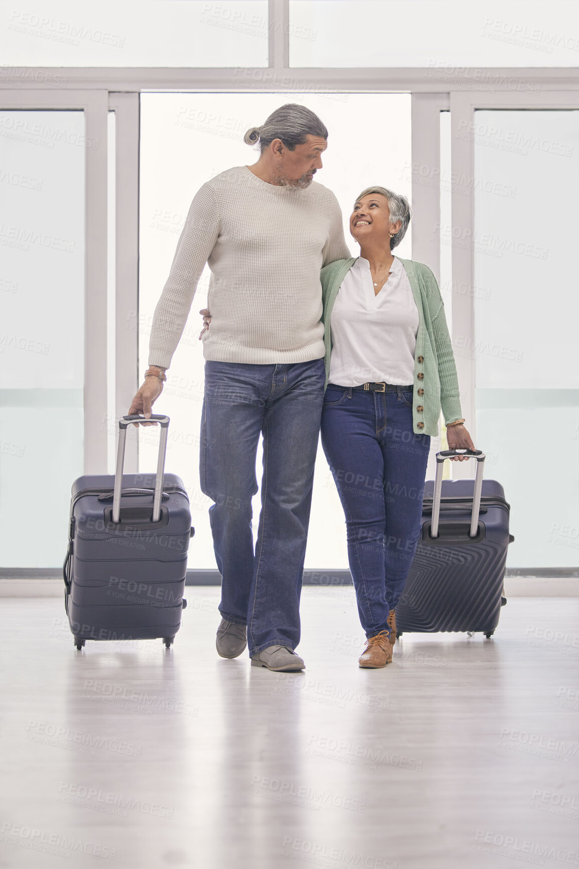 Buy stock photo Mature couple, suitcase and walking in airport lobby, happy and travel together on tourist holiday. Man, woman smile and luggage for flight on vacation, immigration journey and global airplane trip