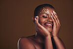 Art, beauty and black woman with gold makeup on brown background, glitter paint and cosmetics mockup. Shine, glow and African model in studio space for fashion, aesthetic freedom and luxury skincare.