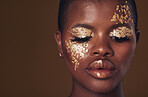 Gold, face and black woman with makeup for beauty aesthetics isolated in a studio brown background eyes closed. Creative, luxury and African person with cosmetic glamour, art or design for skincare