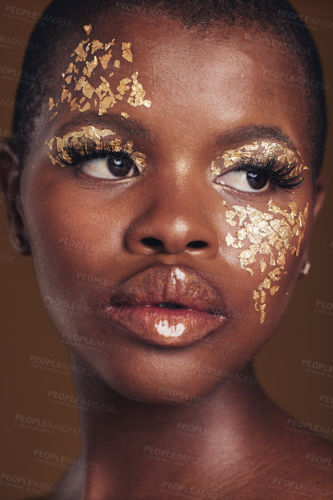 Buy stock photo Art, face of black woman with gold makeup and brown background, glitter paint and cosmetics. Shine, glow and African model in studio on facial beauty, fashion and aesthetic freedom in luxury skincare