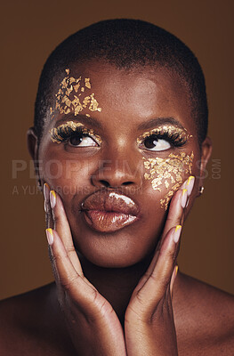 Buy stock photo Art, fun and black woman in gold makeup on brown background, glitter paint or cosmetics. Shine, glow and silly face of African model in studio for beauty, fashion and aesthetic freedom in luxury skin