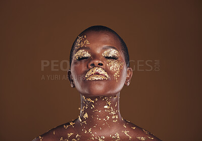 Buy stock photo Beauty, glitter and black woman with gold makeup on brown background with art, paint and cosmetics. Shine, glow and African model in studio for facial fashion, aesthetic freedom and luxury skincare.