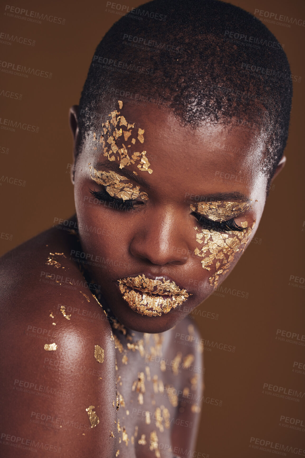 Buy stock photo Art, facial on black woman with gold makeup and brown background, glitter paint and cosmetics. Shine, glow and African model in studio for beauty, fashion and aesthetic freedom in luxury skincare.