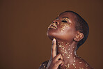 Profile, beauty and black woman with gold makeup, mockup and brown background with art, glitter paint and cosmetics. Shine, glow and African model in studio space for aesthetic, luxury and skincare.