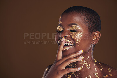 Buy stock photo Happy laugh of black woman with gold makeup, mockup on brown background and glitter paint for cosmetics. Shine, glow and smile, African model in studio for facial beauty and funny aesthetic luxury.