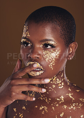 Buy stock photo Beauty, black woman with gold paint makeup and brown background with glitter, art and cosmetics. Shine, glow and face of African model in studio for skincare, aesthetic and luxury facial with color.