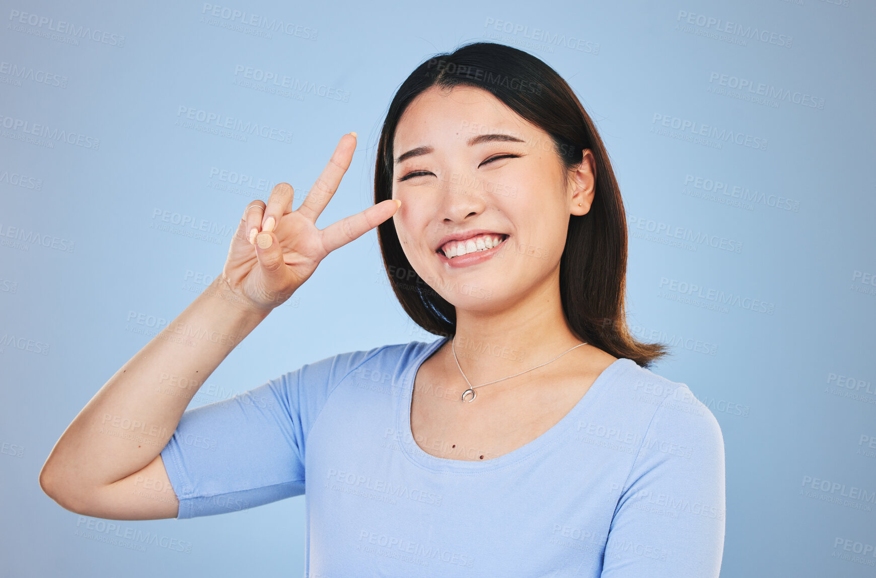 Buy stock photo Peace, sign and portrait of woman with hand for emoji in studio blue background with gen z style, fashion or happiness. Face, smile and Asian model with gesture, expression