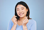 Happy asian woman, hands and love sign or gesture in romance against a blue studio background. Face of calm female person smile in happiness with loving emoji, icon or symbol for valentines day