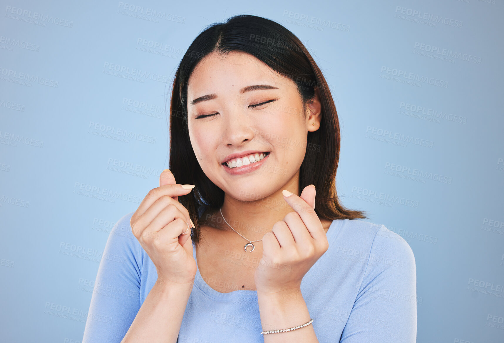 Buy stock photo Happy asian woman, hands and love sign or gesture in romance against a blue studio background. Face of calm female person smile in happiness with loving emoji, icon or symbol for valentines day