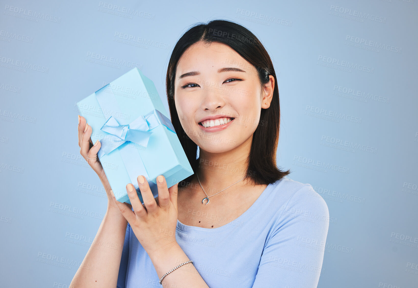 Buy stock photo Happy, Asian woman and portrait with a gift, box and present on blue background in studio with promotion or discount. Model, smile and face with happiness for giving or receiving surprise package