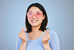 Happy asian woman, portrait and sunglasses with love hands, sign or gesture against a blue studio background. Female person smile in happiness with loving emoji, icon or symbol for valentines day