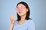 Peace, sign and portrait of woman with hand for emoji in studio blue background with gen z style, fashion or heart glasses. Face, pose and Asian model with cool gesture and expression on social media