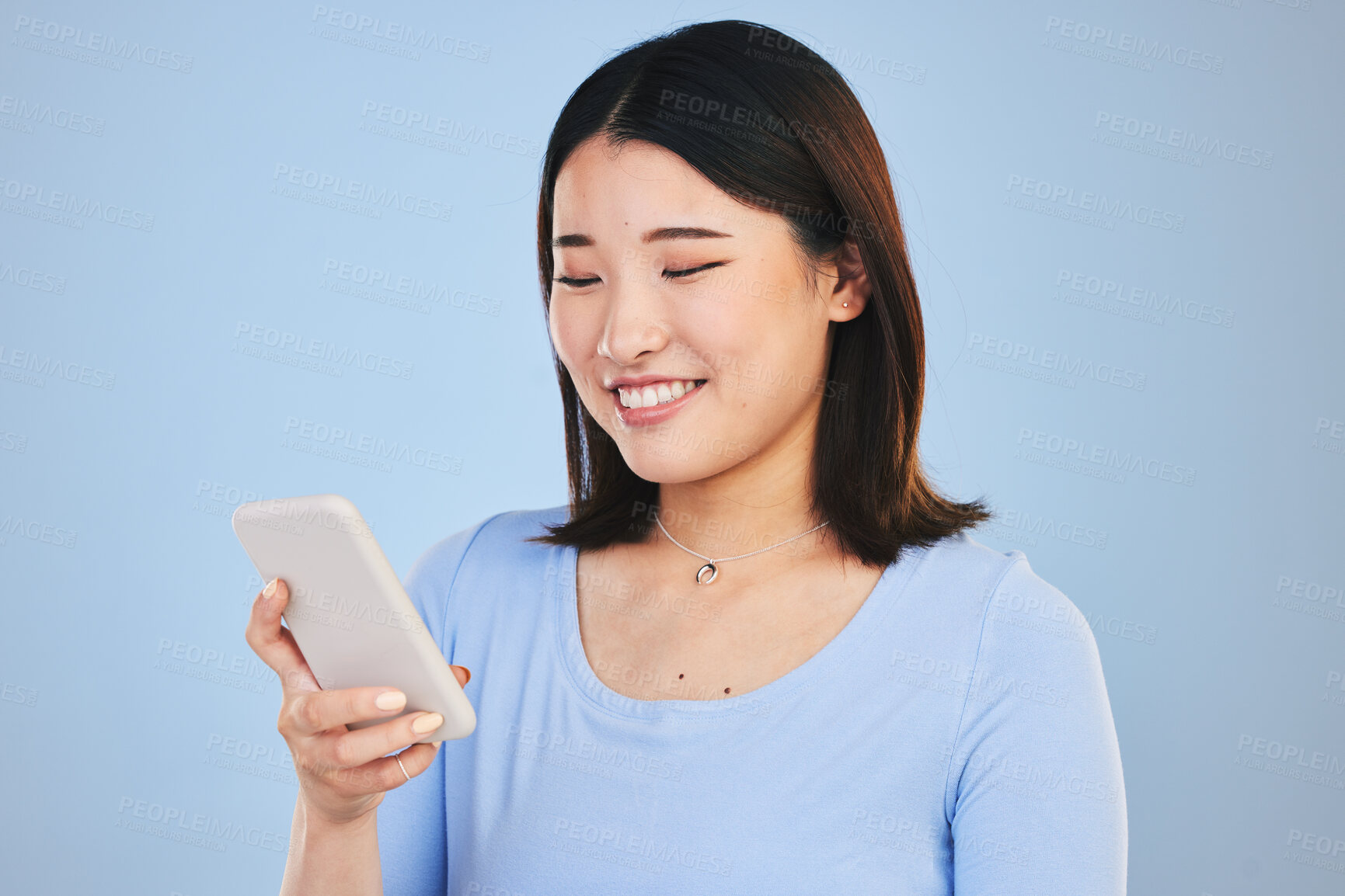Buy stock photo Happy asian woman, phone and typing in social media, networking or communication against a blue studio background. Female person smile in online research, chatting or texting on mobile smartphone app