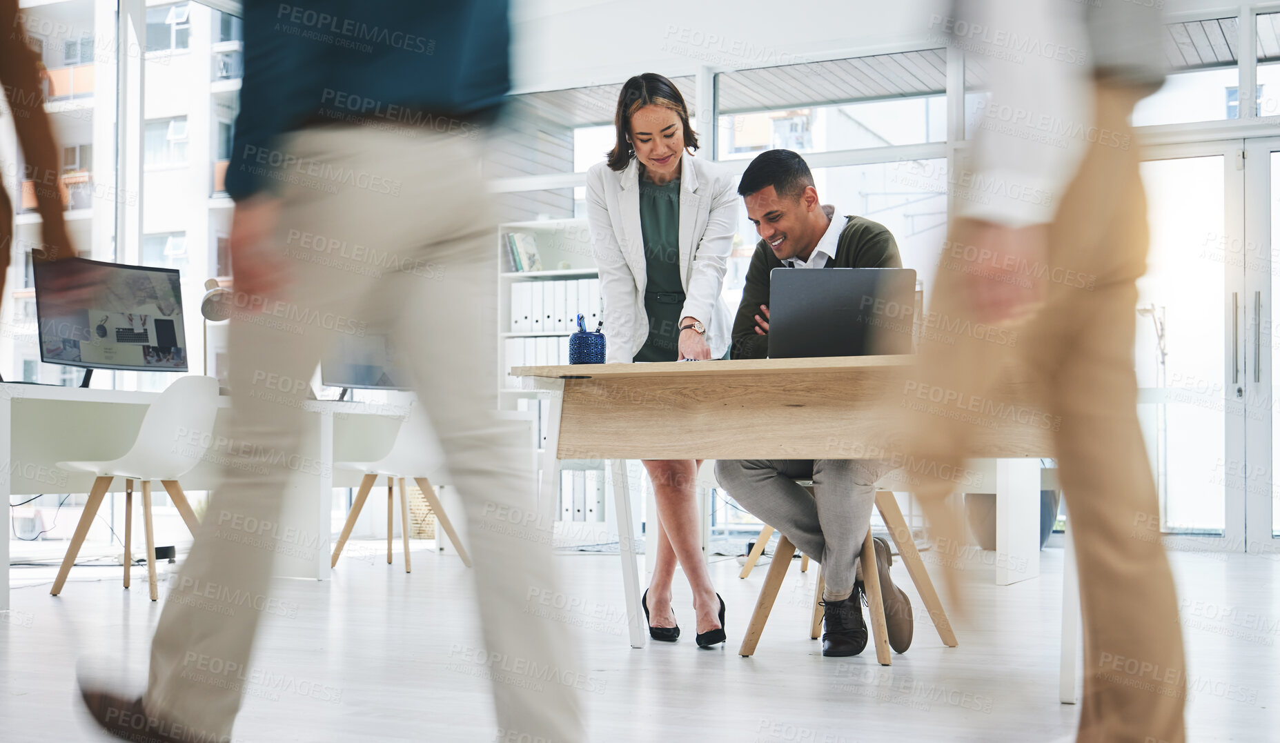 Buy stock photo Collaboration, man and woman in busy office with laptop, advice and project management. Meeting at desk, opinion and businessman with mentor, business people walking and employees at startup agency.