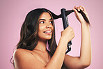 Woman, hair and care with iron in studio for beauty, cosmetic treatment and shine on pink background. Face of young model, hairstyle and heating equipment of electrical tools for aesthetic texture 