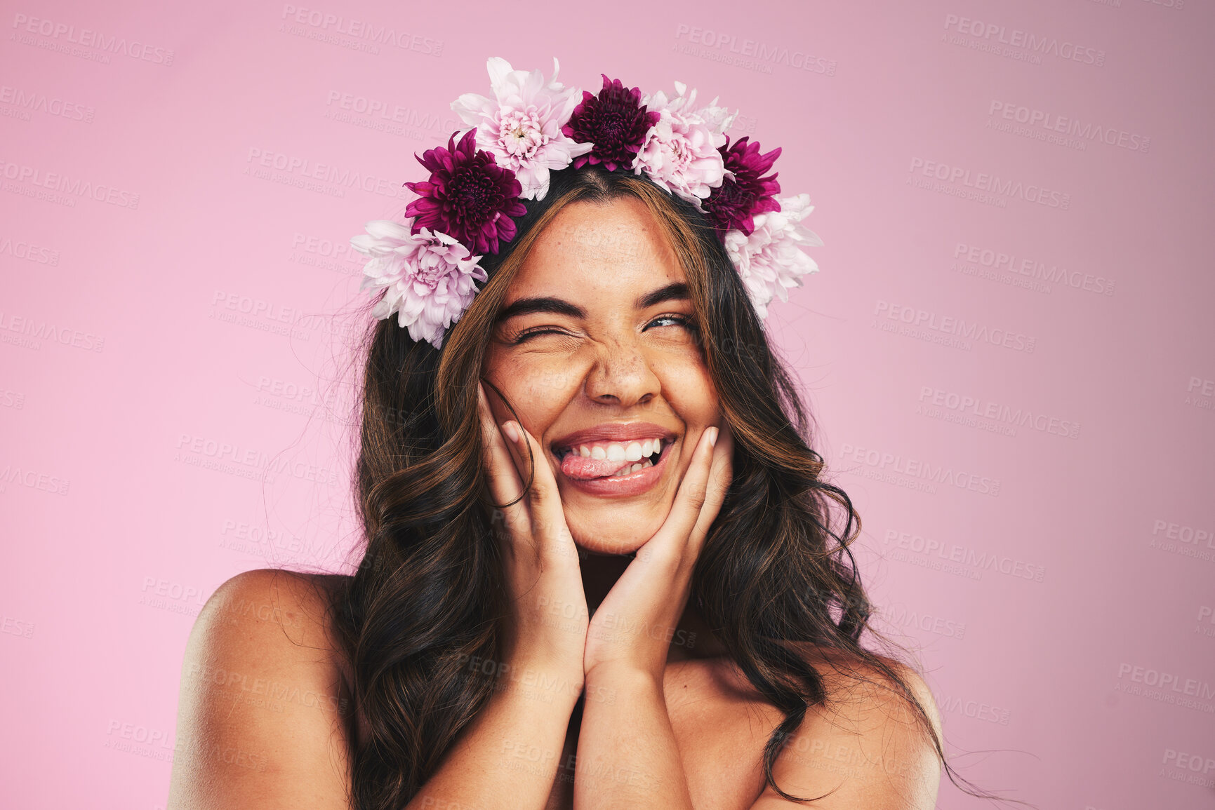 Buy stock photo Beauty, flowers and wink with hairstyle of woman in studio for cosmetics, skincare and wellness. Self care, spa treatment and crown with face of person on pink background for spring, glow and makeup 