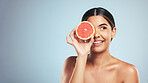 Skincare, grapefruit and woman in studio for natural cosmetic, treatment or beauty on grey background. Citrus, facial and model with fruit for vegan, detox and vitamin c, glowing skin or collagen
