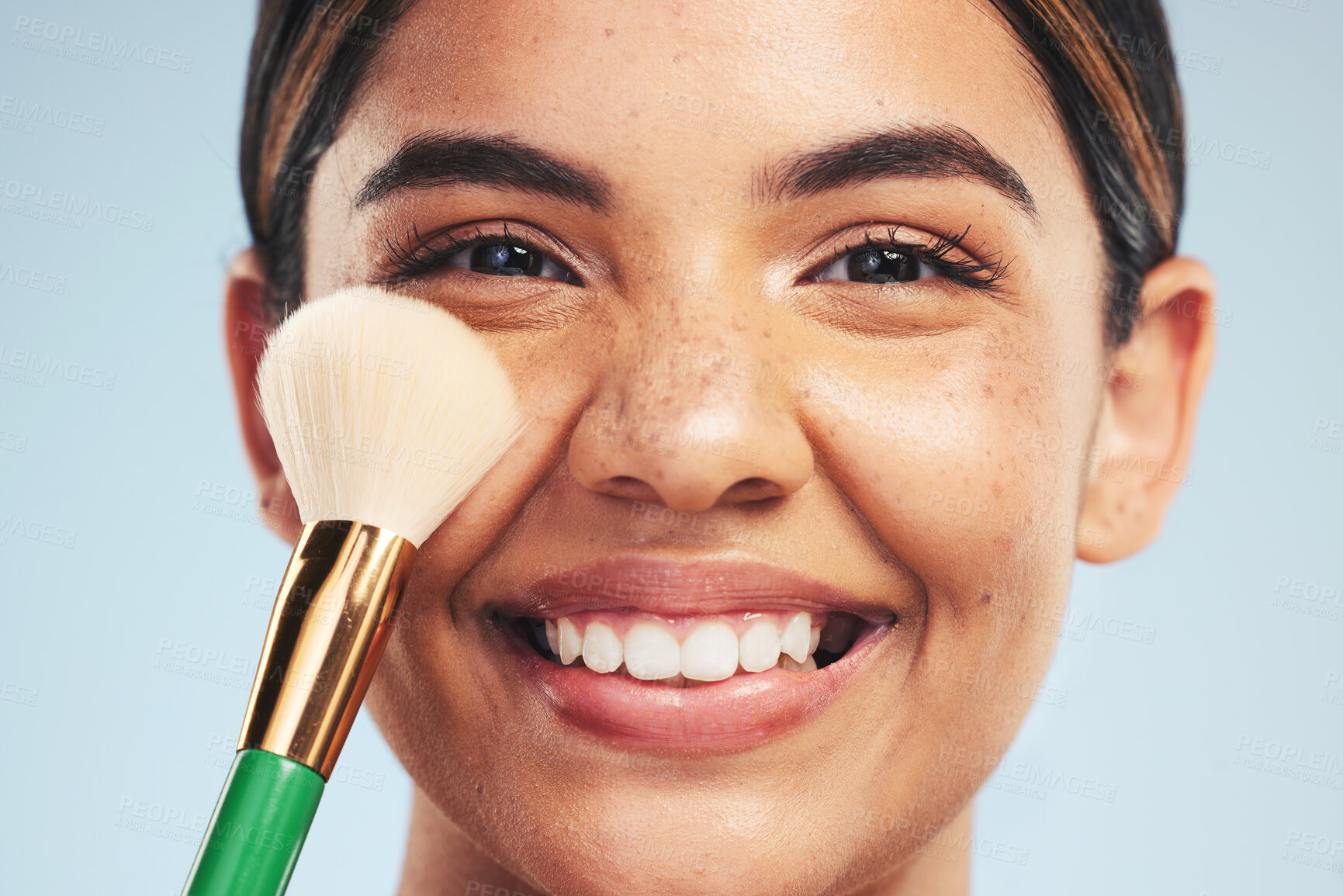 Buy stock photo Portrait, happy woman and brush for makeup in studio, apply foundation and glow on blue background. Closeup face of model smile for aesthetic cosmetics, skincare tools and beauty powder for makeover 