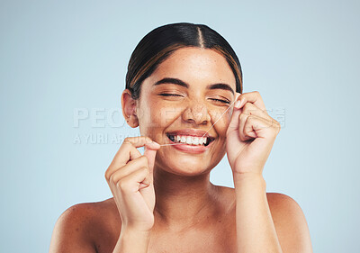 Buy stock photo Woman, smile and floss teeth in studio for dental hygiene, care and gum gingivitis on blue background. Happy female model cleaning mouth with oral thread for fresh breath, healthy habit and grooming 