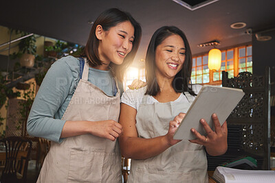 Buy stock photo Restaurant, tablet and asian women checking sales, booking or menu promo for small business at counter. Social media, food review and startup cafe owner with waitress scroll on digital app together.