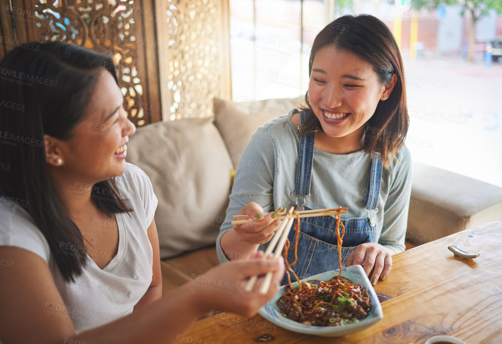 Buy stock photo Chopsticks, restaurant and girl friends eating noodles and Asian cuisine at a cafe. Happy, hungry women and plate of food at a Japanese bar with friendship, smile and bonding from meal at a table