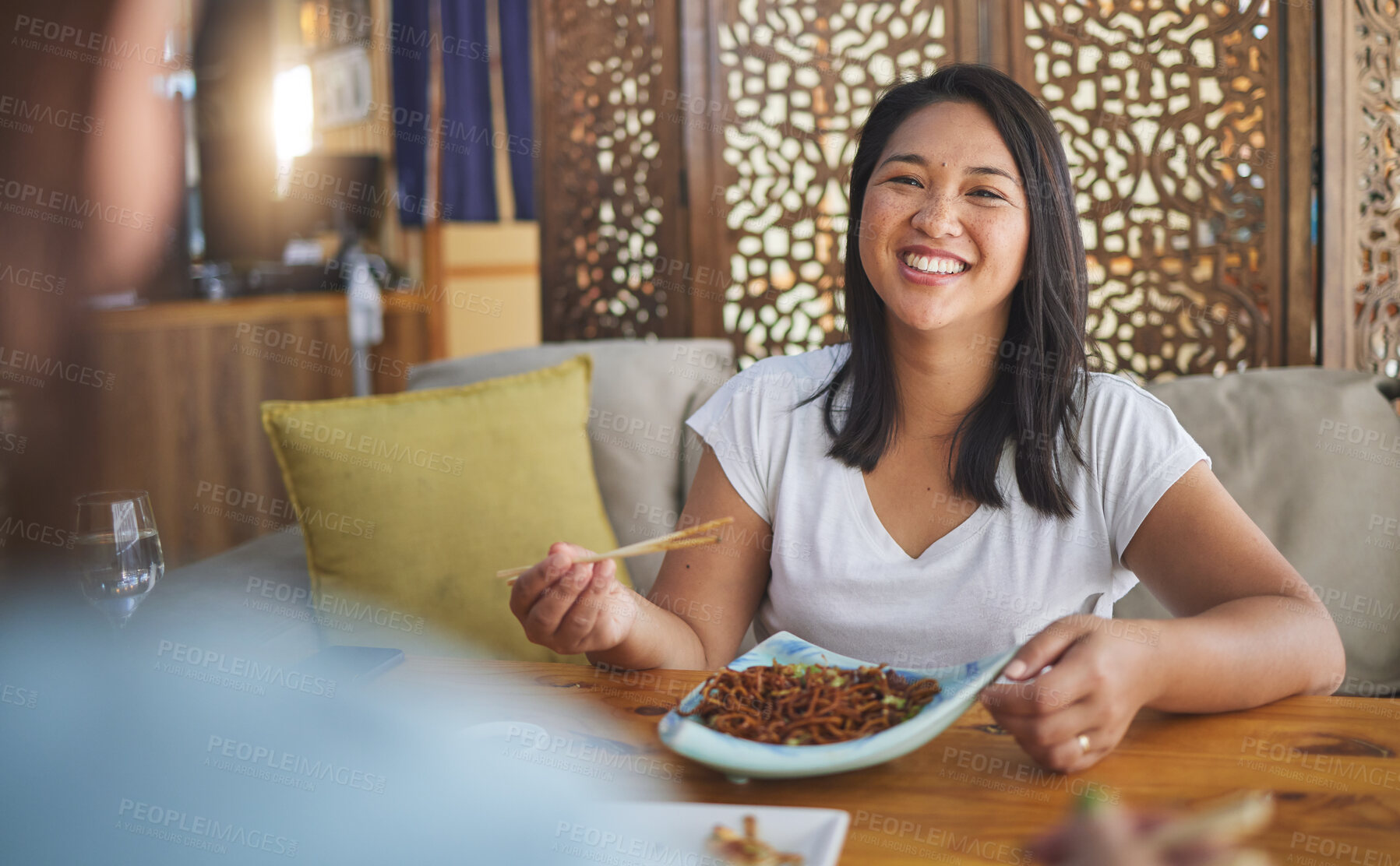 Buy stock photo Asian, food and woman on restaurant date eating for dinner or lunch meal using chopsticks and feeling happy with smile. Plate, young and person enjoy Japanese cuisine, noodles or diet at a table