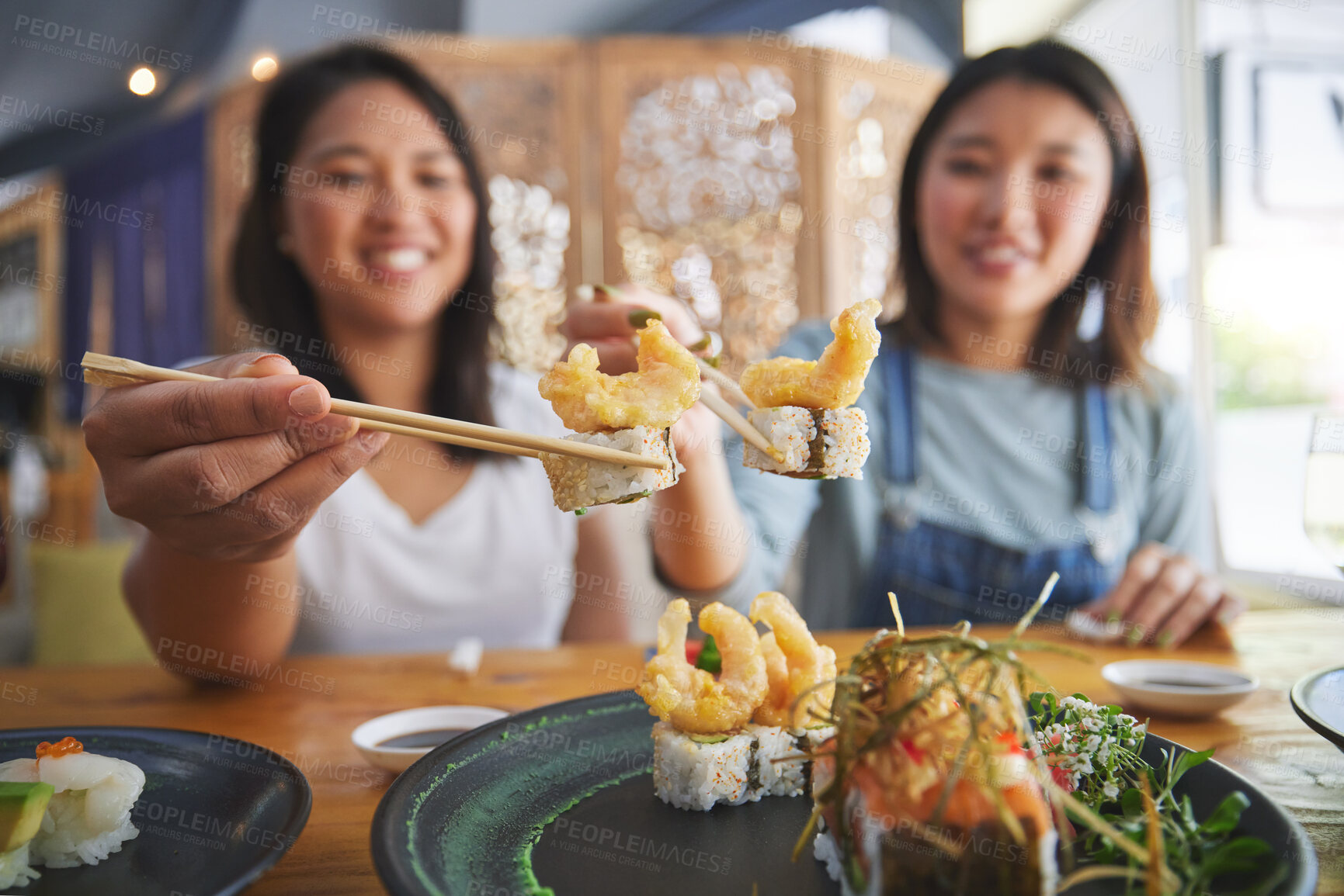 Buy stock photo Chopsticks, girl friends and shrimp sushi at a table with salmon and Japanese cuisine food at restaurant. Young women, eating and tempura prawn with fish for lunch and meal on a plate with a smile