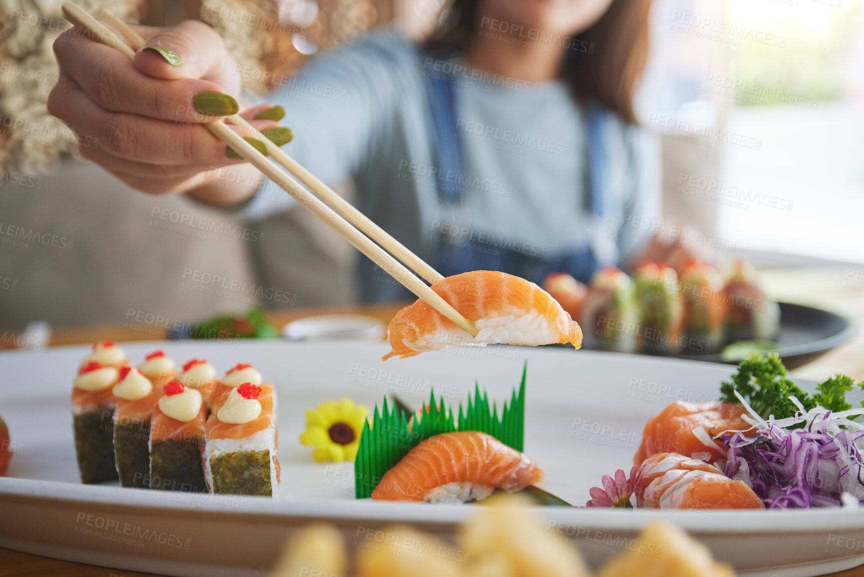 Buy stock photo Hands, chopsticks and woman with sushi in restaurant, fine dining and eating in cafe store. Salmon, stick and person on fish, meat and tempura food in plate for lunch, brunch and healthy seafood meal