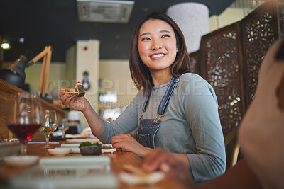 Buy stock photo Asian, sushi and woman at a restaurant eating for dinner or lunch meal using chopsticks and feeling happy with smile. Plate, young and person enjoy Japanese cuisine, noodles or diet at a table