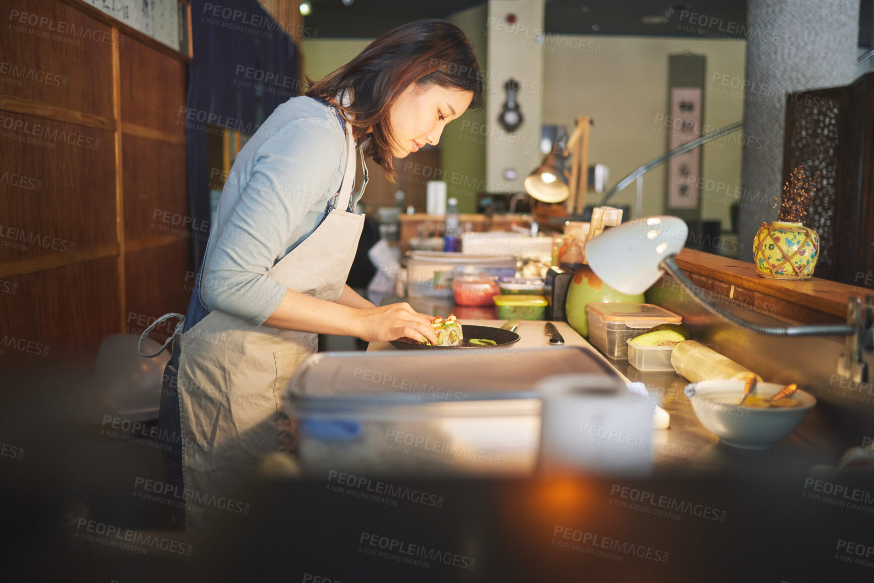 Buy stock photo Chinese food, chef and an asian woman in a sushi restaurant to serve a traditional meal for nutrition. Kitchen, cooking or preparation with a happy young employee in an eatery for fine dining cuisine