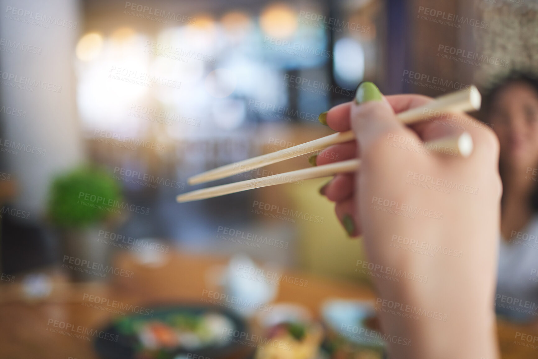 Buy stock photo Tradition, bamboo chopsticks and hand of a person eating Japanese food at a restaurant for nutrition. Closeup of a woman with wooden sticks or utensil for dining, culture and cuisine for diet