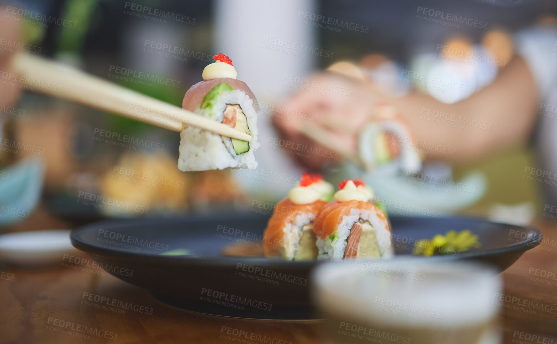 Buy stock photo Chopsticks, food and eating sushi at a restaurant for nutrition at table. Closeup of hungry people with wooden sticks and soy sauce for dining, Japanese culture and cuisine with creativity on a plate