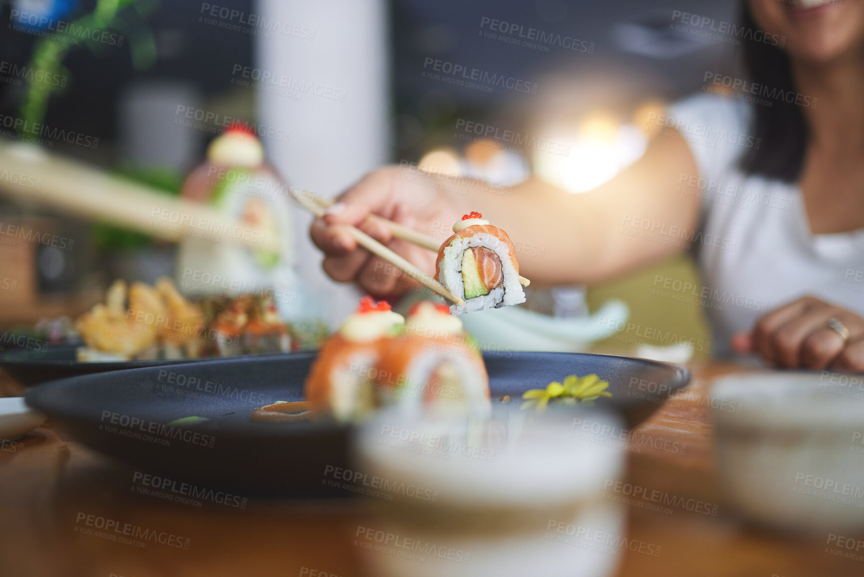 Buy stock photo Chopstick, hand and eating sushi food at restaurant for nutrition at table. Closeup of hungry people with wooden sticks for dining, Japanese culture and cuisine while sharing with creativity on plate