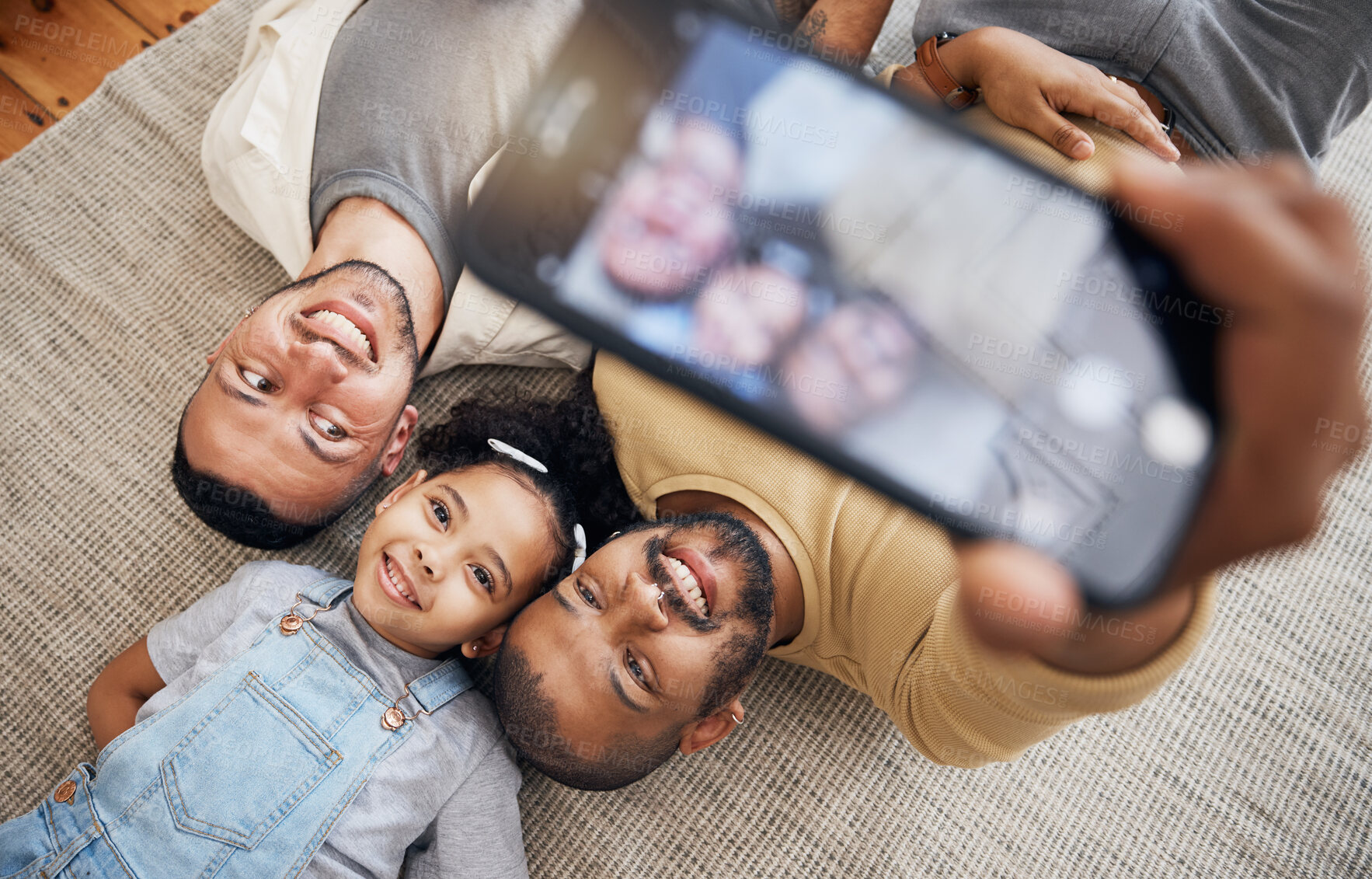 Buy stock photo Selfie, gay father and blended family with a girl lying together on the floor of the home for a picture from above. LGBT love, children or kids and a daughter with her happy parents for a photograph