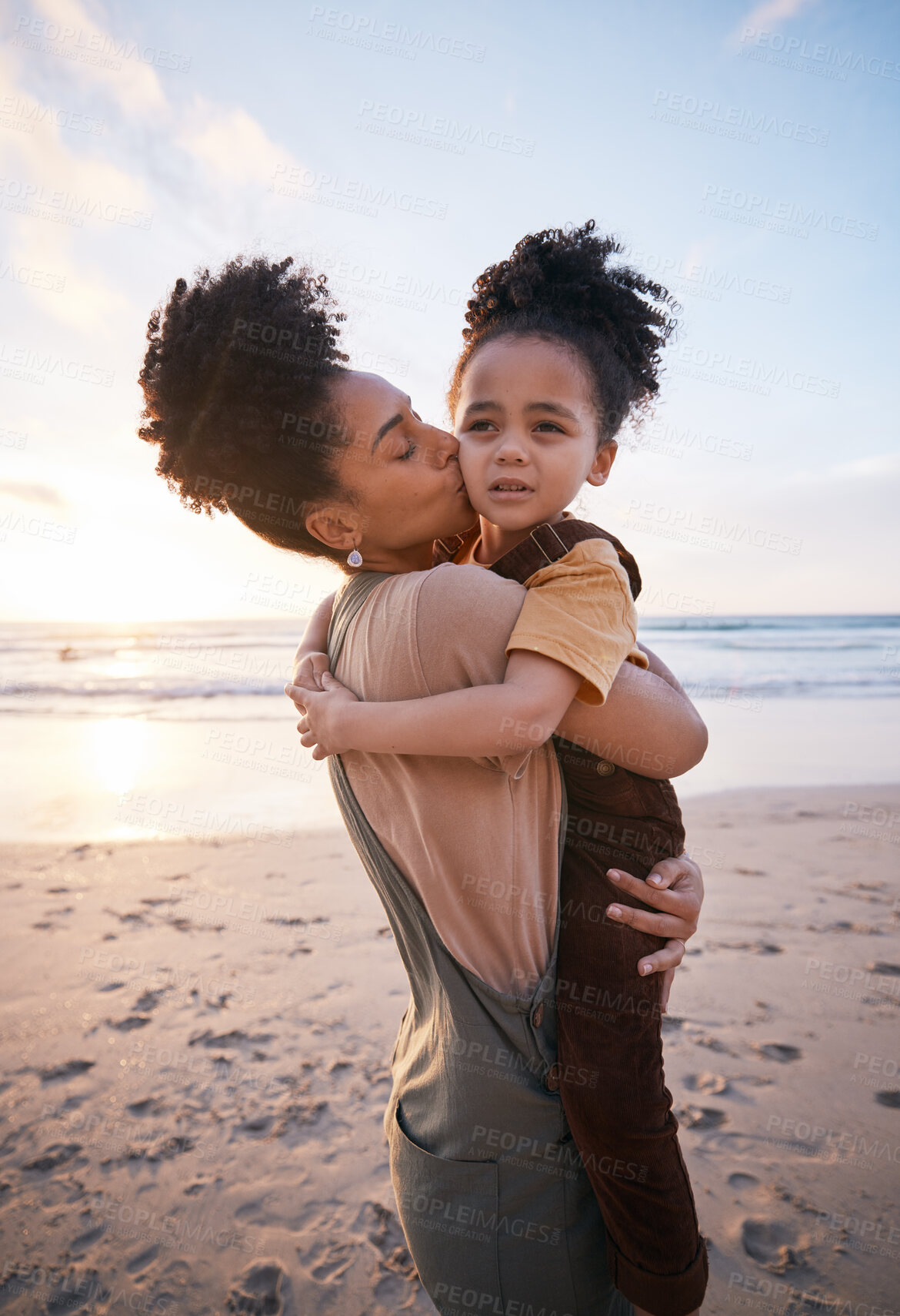 Buy stock photo Beach, sunset and mother kissing her child on a family vacation, holiday or travel adventure. Love, care and mom holding, hugging and bonding with her girl kid by the ocean on weekend trip in Mexico.