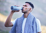 Fitness, exercise and a man drinking water outdoor on a break or rest after run, workout or training. Tired athlete person or runner in nature with a bottle for thirst, cardio or health and wellness