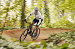 Blurred trees, cycling and man in nature training for a race, marathon or competition in forest. Fast, fitness and male cyclist athlete riding bicycle at speed for cardio exercise or workout in woods