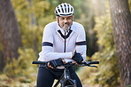 Fitness, portrait and senior man with bicycle in a forest for cycling, sports or training for off road hobby in nature. Face, smile and happy cyclist with mountain bike in a park for biking adventure