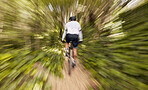 Blur motion, cycling and man in nature training for a race, marathon or competition in a forest. Fast, fitness and back of male cyclist athlete riding bicycle at speed for cardio exercise or workout.