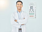 Ophthalmologist, portrait and man with arms crossed in hospital mockup space for healthcare of vision. Face, confident optometrist and happy doctor, Asian optician or medical professional in Cambodia