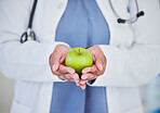 Doctor, hands and apple in healthcare diet, natural nutrition or healthy vitamin food at the hospital. Closeup of medical professional holding organic green fruit for health and wellness at clinic