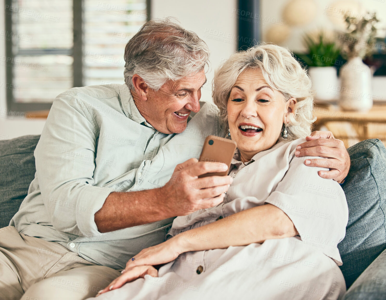 Buy stock photo Relax, phone and funny with old couple on sofa for streaming, social media and communication. Excited, internet and website with senior man and woman laughing in living room at home for news and app