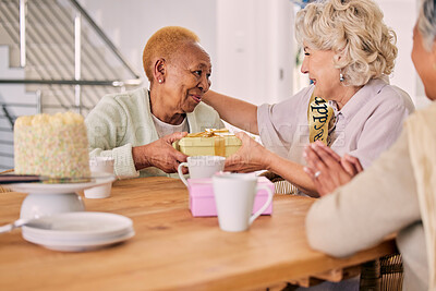 Buy stock photo Senior friends, birthday cake and women celebration at a home with a present and gift with people. Surprise, giving and party of elderly group at a dining room table together in retirement with smile