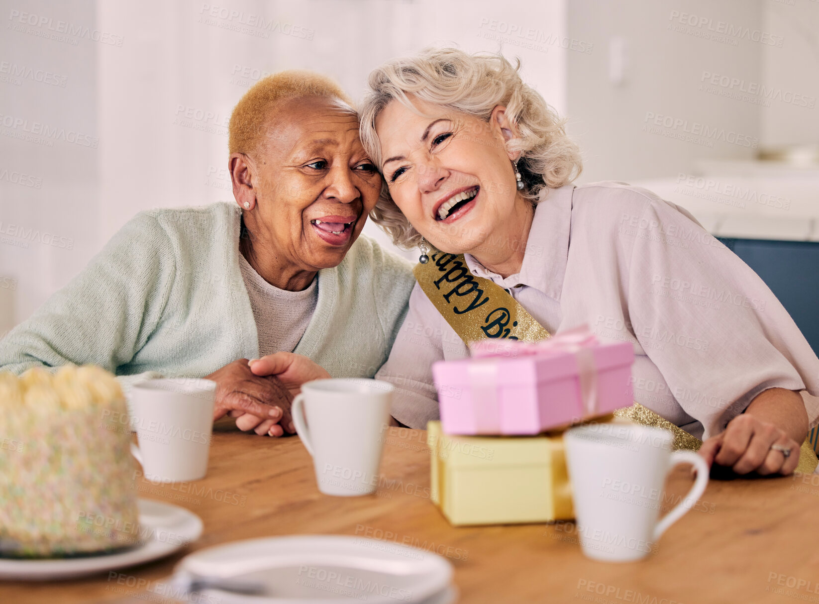 Buy stock photo Senior women, birthday celebration and party event at a home with a present and friends gift. Surprise, happy singing and retirement of elderly people at a dining room table together with a smile