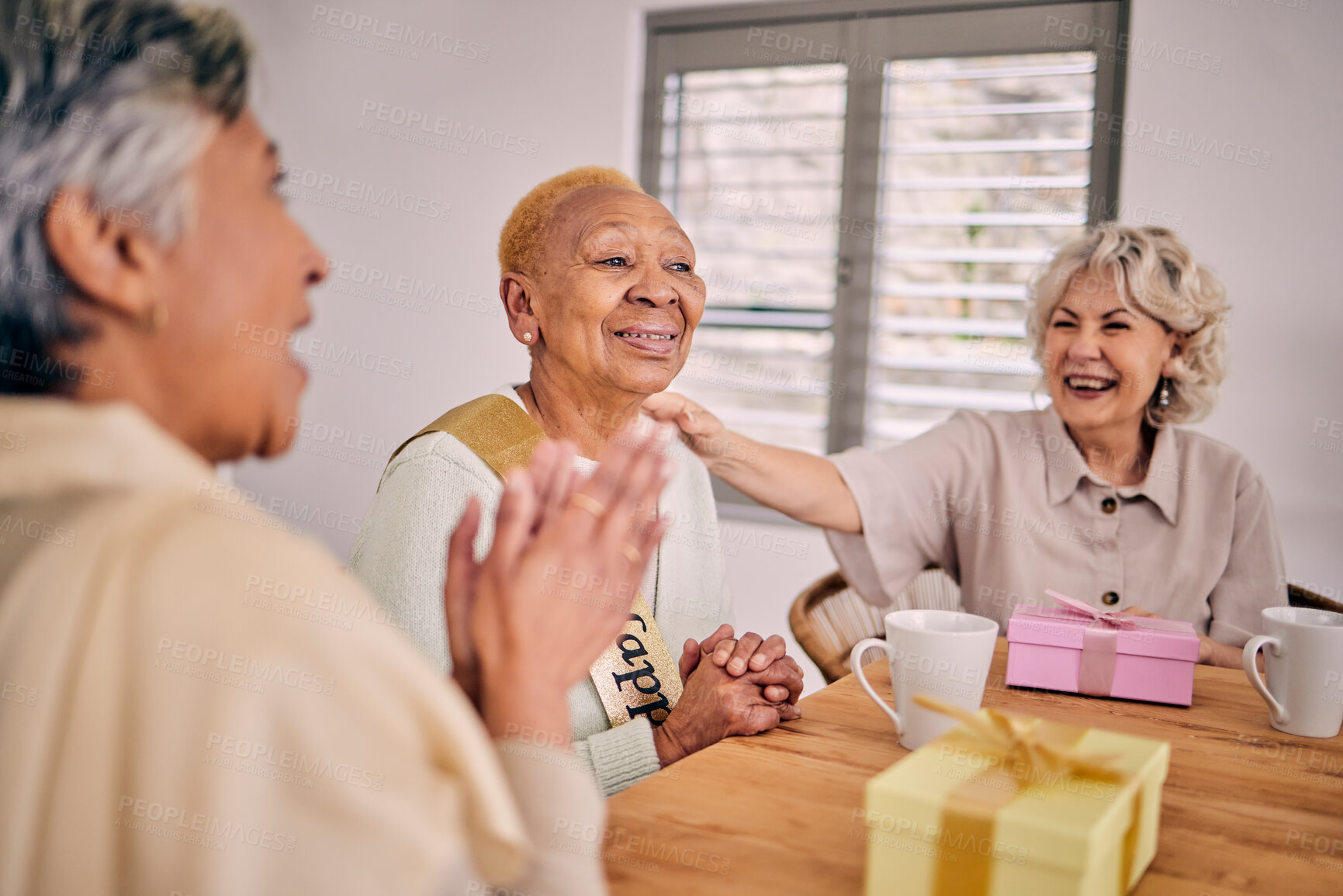 Buy stock photo Senior friends, birthday singing and party at a home with a present and gift with excited people. Surprise, celebration and retirement of elderly group at a dining room table together with a smile