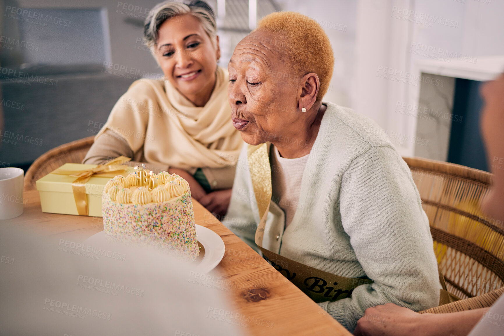 Buy stock photo Senior woman blowing candles on her cake for birthday celebration at a house at a party with friends. Smile, happy and elderly female person with a dessert to celebrate with people in retirement home