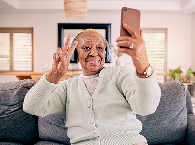 Buy stock photo Headphones, selfie and senior woman with peace sign in home listening to music, audio and radio on sofa. Retirement, emoji and happy person in living room take photo for social media and online post