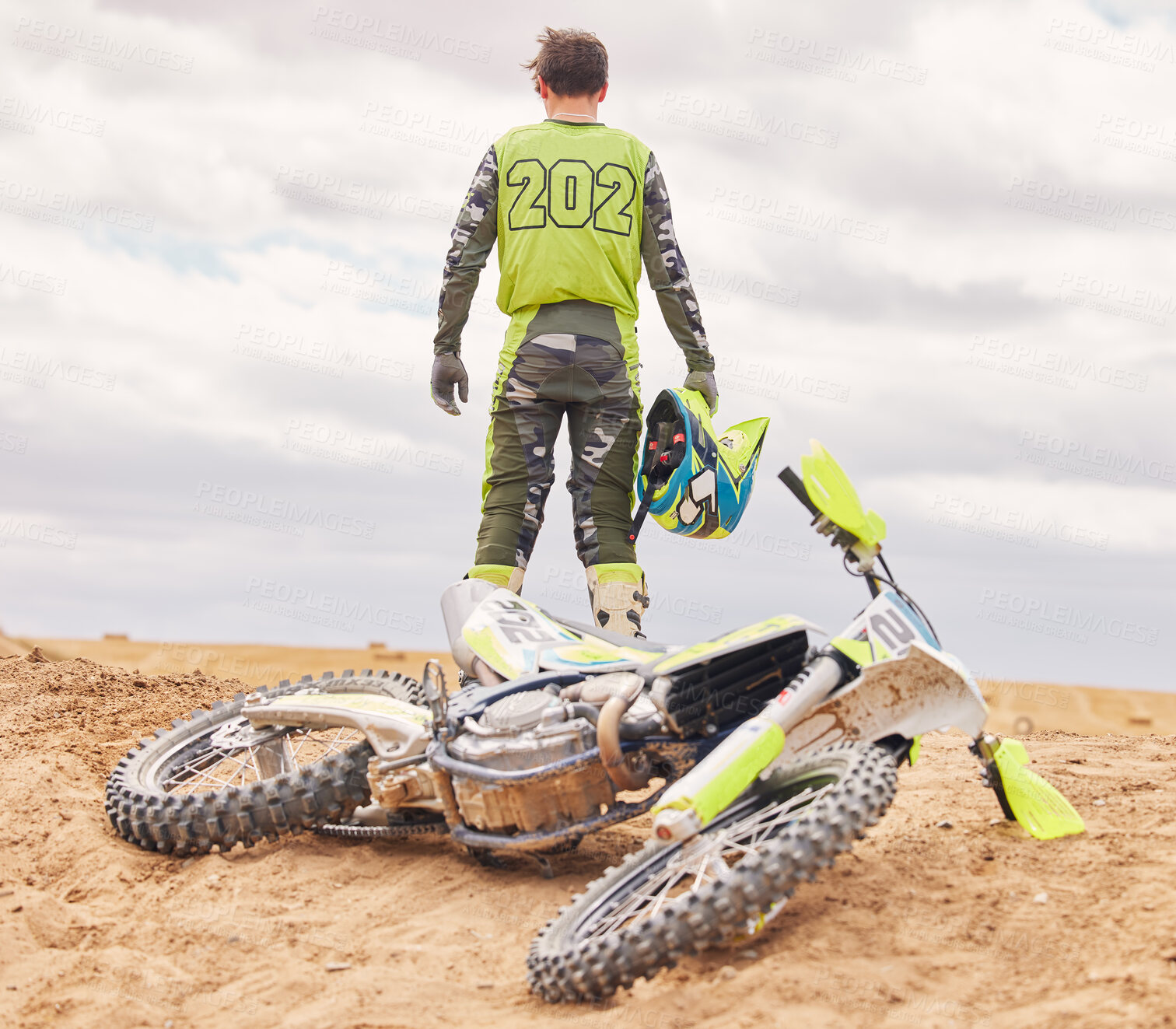 Buy stock photo Bike. sand and the back of a sports man outdoor on a dirt track after an accident or fall during a race. Motorcycle, freedom and challenge with a male athlete against a gray sky in the desert